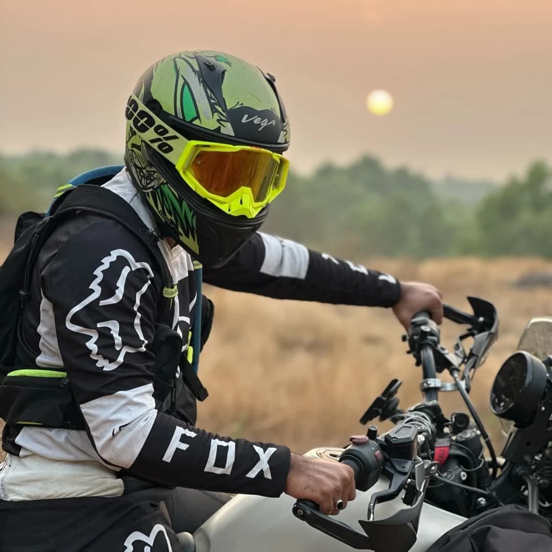 Rider in a green helmet and goggles on an adventure bike at sunset