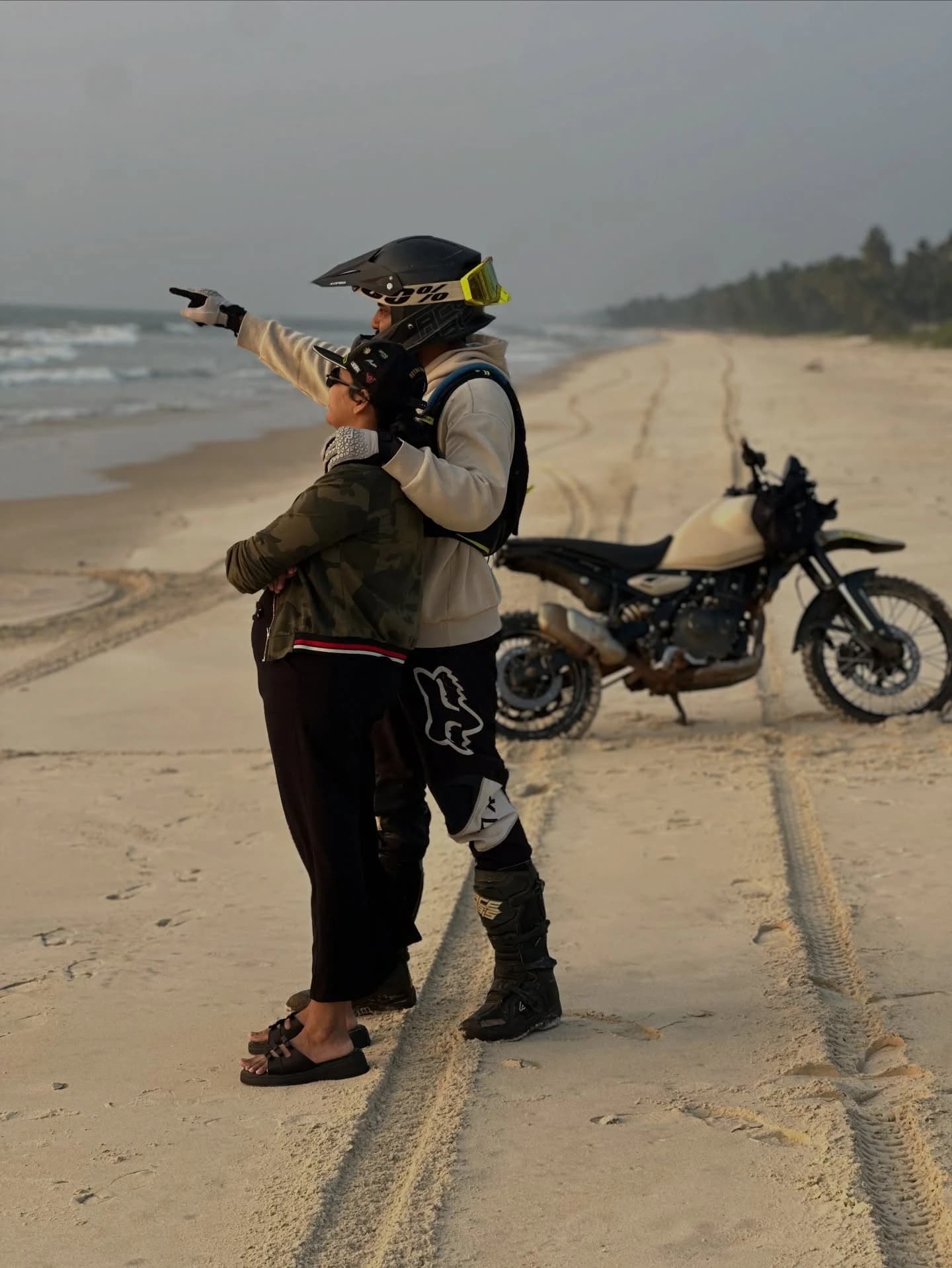 Riders on a beach beside their adventure motorcycle